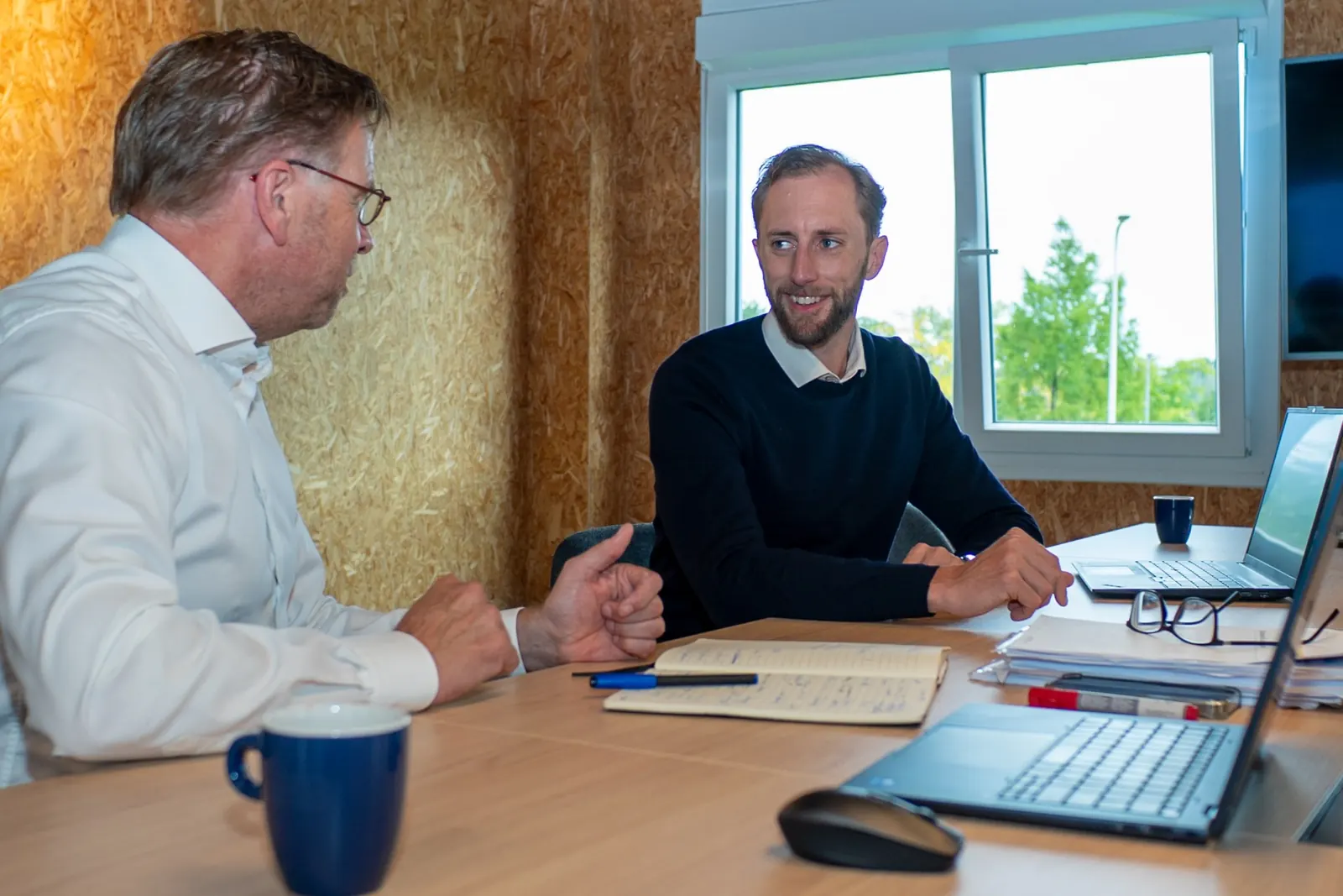 Paul Hoffman in conversation at a table, with laptops and notes within reach
